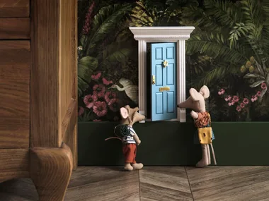 Toy mice in front of a miniature blue door.