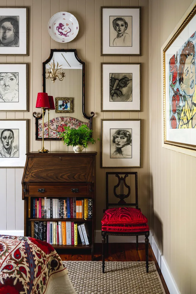 A wall gallery with charcoal drawings over a vintage style cabinet.