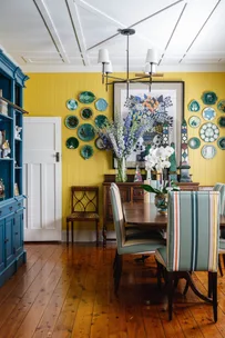 A yellow dining room with a wooden dining table and flooring and a blue cabinet.