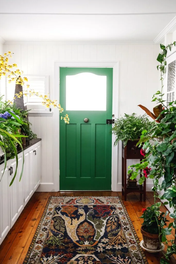 An entry hall with a bright green door surrounded by plants.