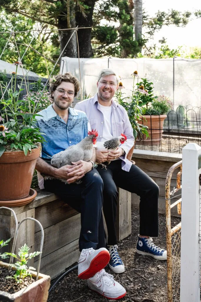 Owners David and Lloyd holding chickens in the garden.