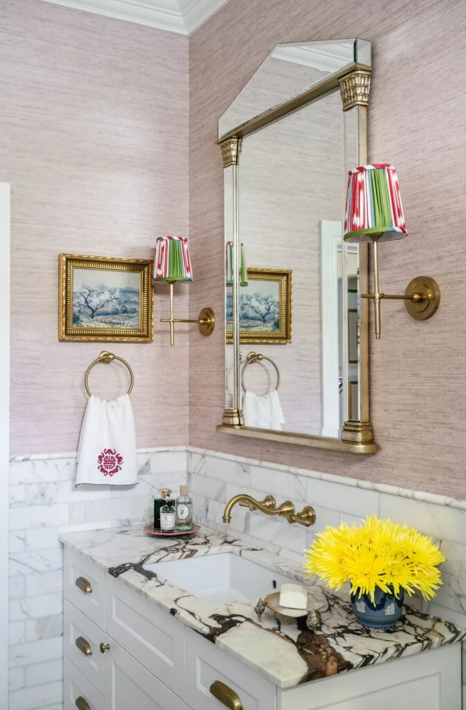 Pink wallpapered bathroom walls above a marble vanity.