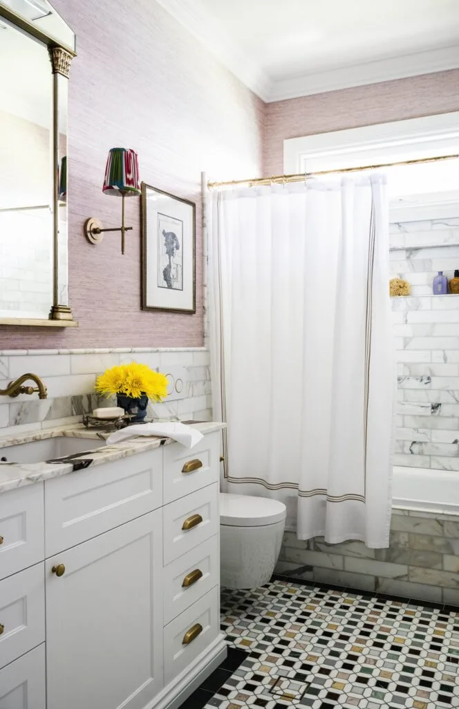 A pink and white marble bathroom with mosaic floor tiles.