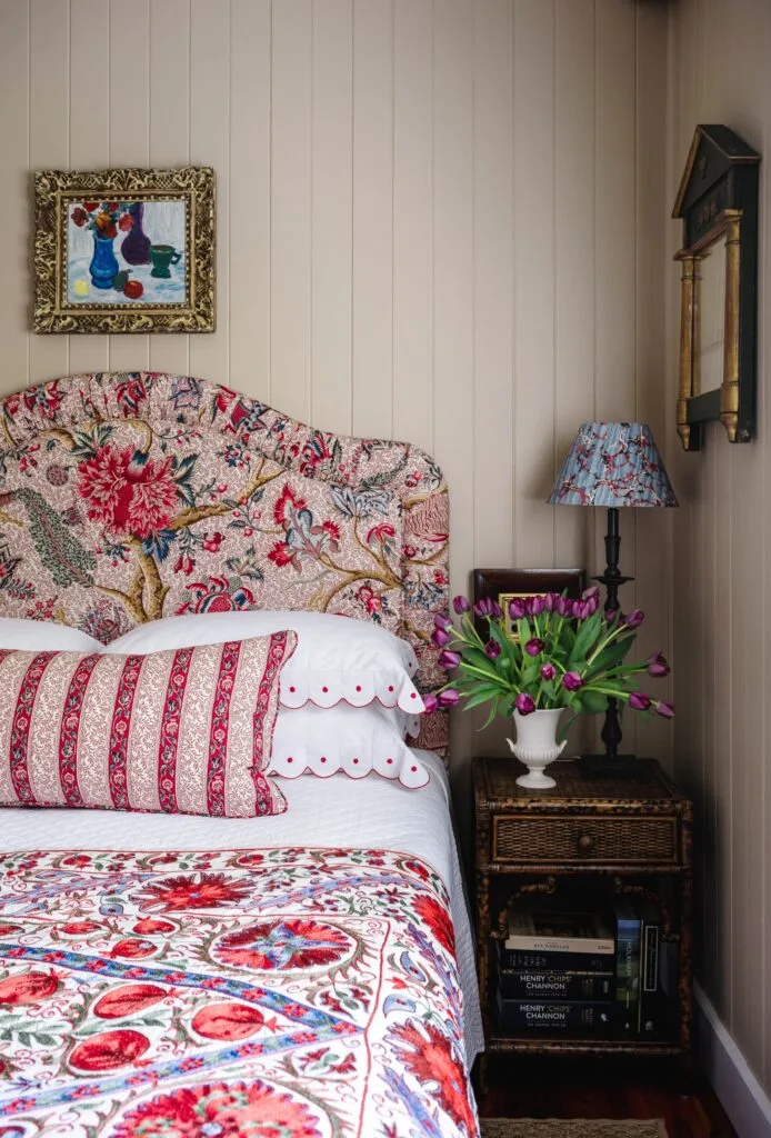 A guest bedroom with light pink panelled walls and a floral printed bed.