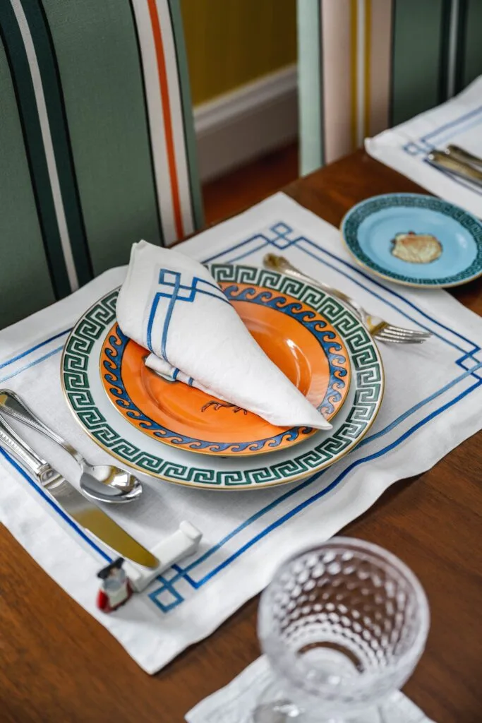 An orange and green plate set on a placemat on the dining table.