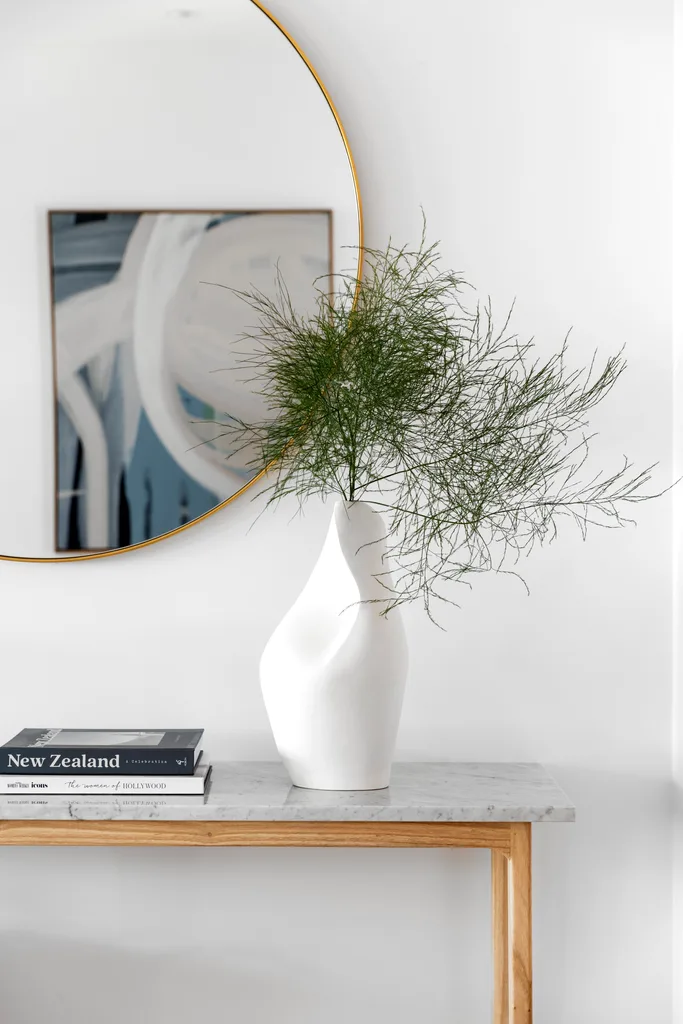 A sculpted white vase on a grey marble console.