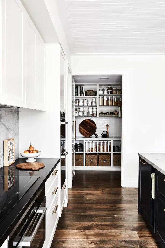 A modern black and white kitchen with a walk-in pantry.