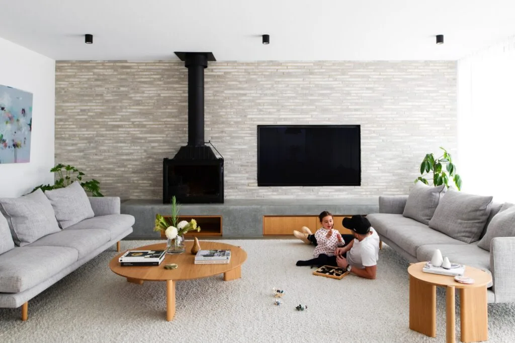 Owner Ed with daughter Hazel playing in the grey minimalist living room.