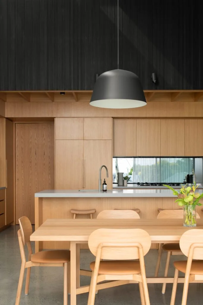 The timber dining table next to the modern minimalist kitchen.