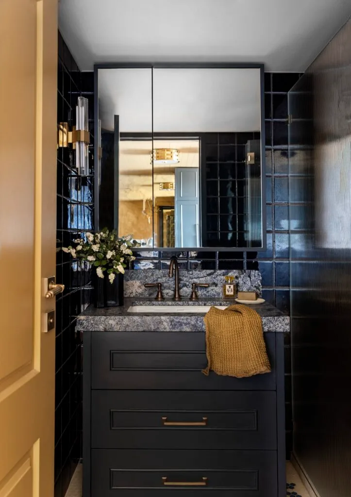 A moody blue and yellow bathroom with a marble-topped vanity.