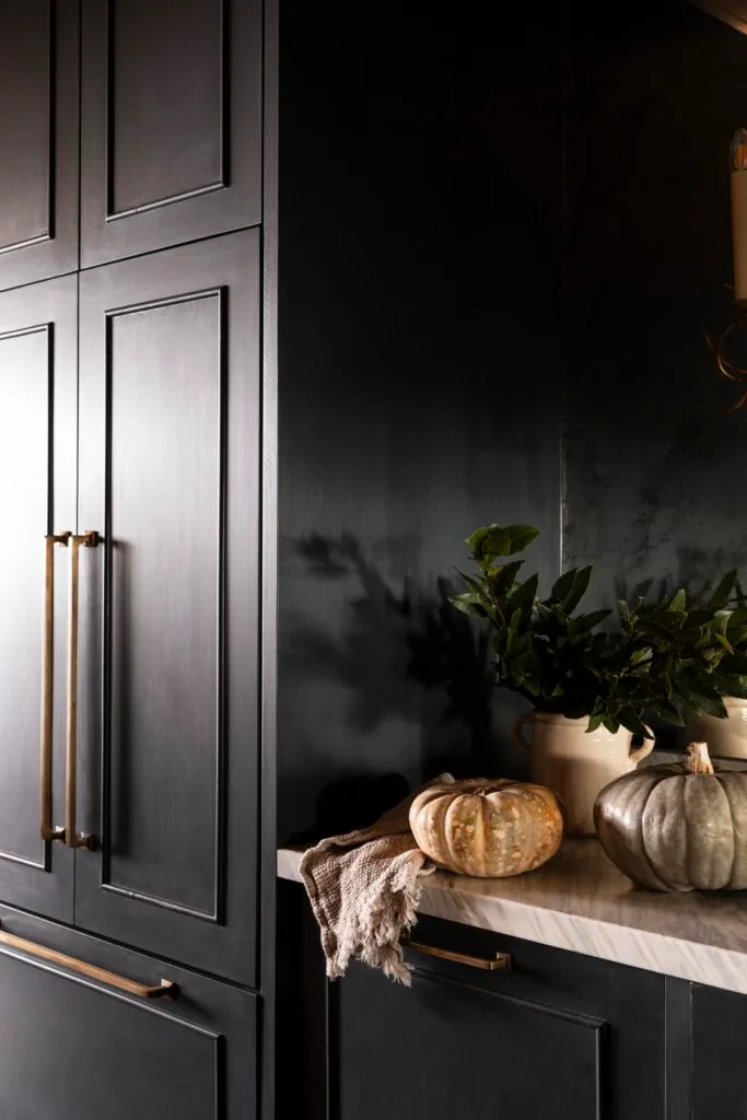 Dark blue shaker-style cabinets and a marble benchtop with pumpkins.