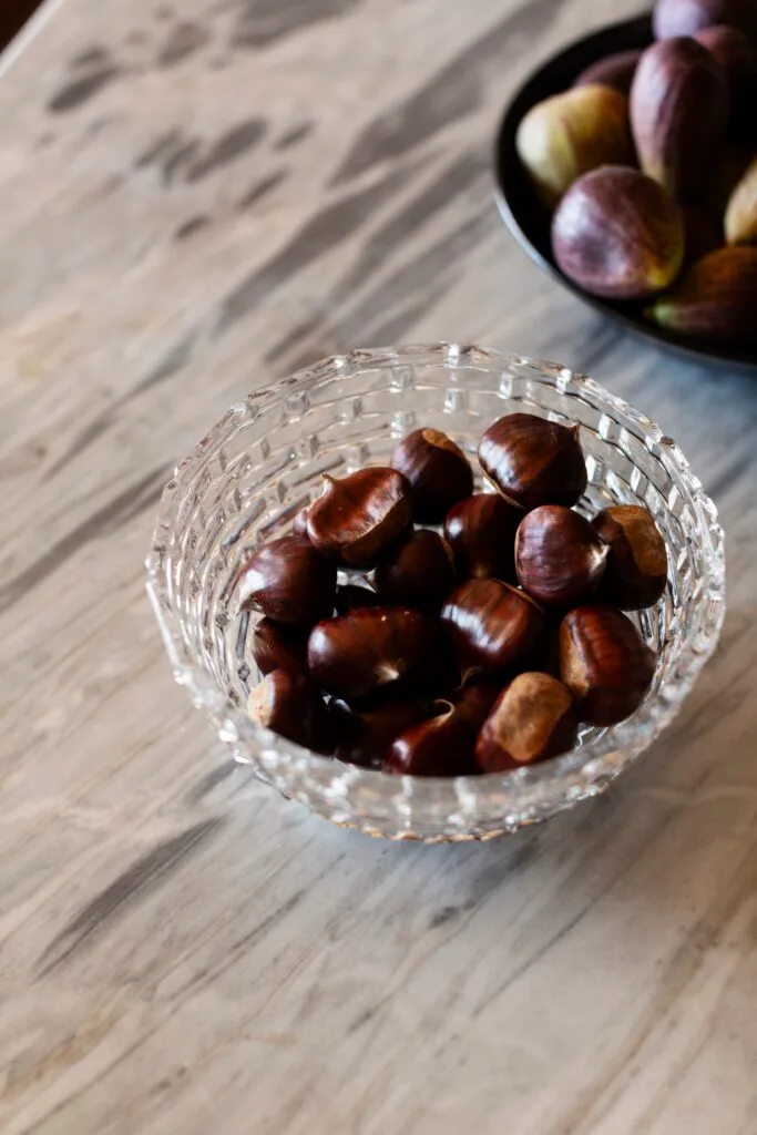 A bowl of chestnuts on a marble table.