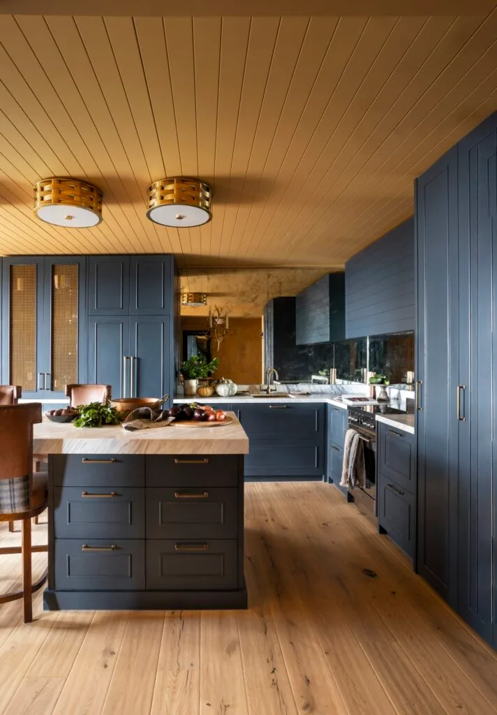 A yellow and dark blue kitchen with timber floors.