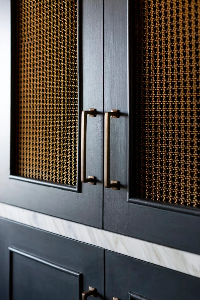 A navy kitchen cabinet with bronze mesh inlays.