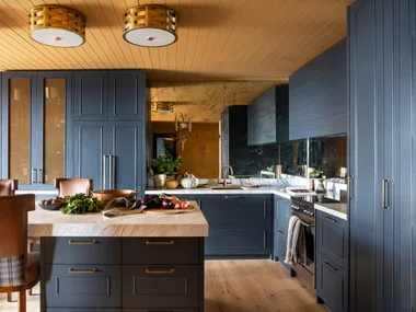 A yellow and dark blue kitchen with timber floors.
