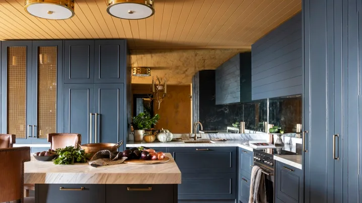 A yellow and dark blue kitchen with timber floors.