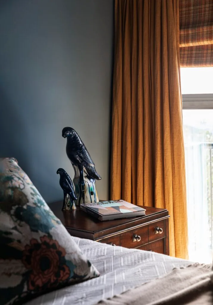 A bird statue on a timber bedside table.