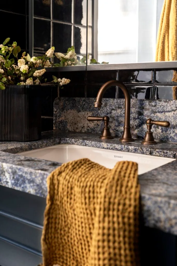 A stone-topped vanity with brass tapware.