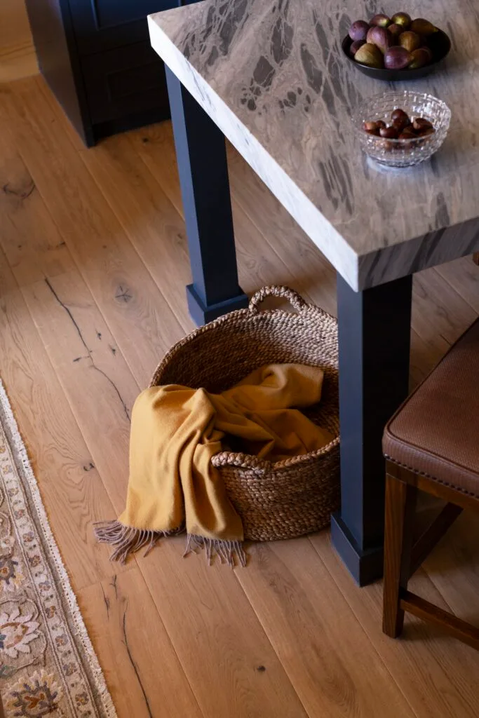 A basket beneath a marble-topped dining table.