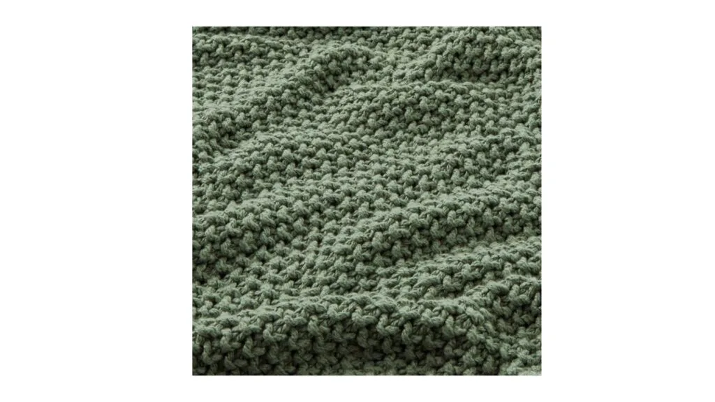 A close-up of the Hallstatt chunky knit throw in Lilypad, which is a moss green.