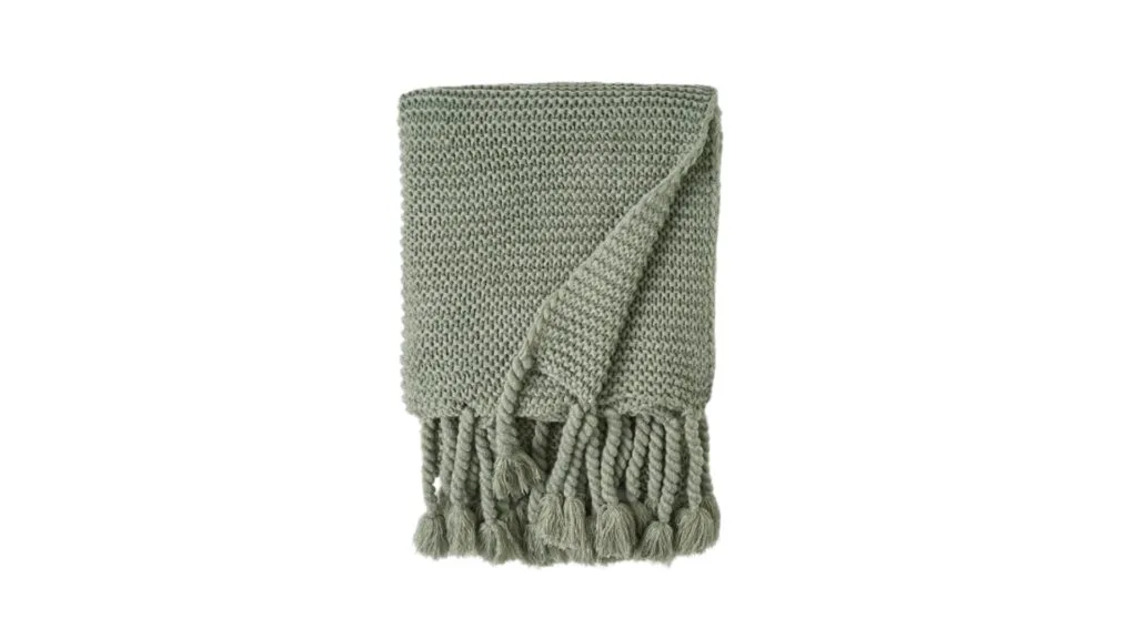 The Bed Bath N' Table chunky knit blanket throw with tassels in Pale Sage, folded up.