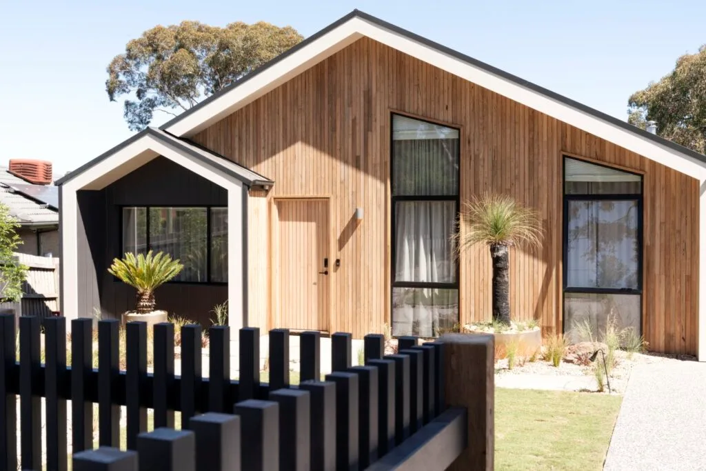 Elle's home is cladded in timber with a black picket fence