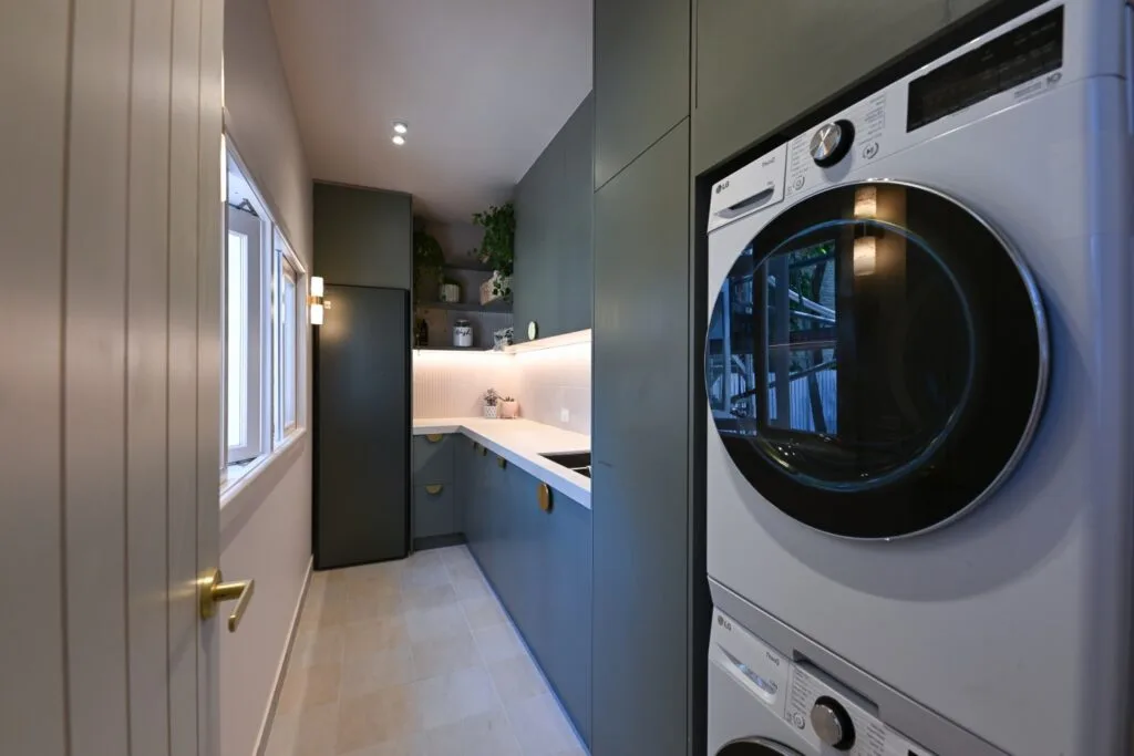 Hannah and Jonny's Dream Home laundry with forest green cabinetry.