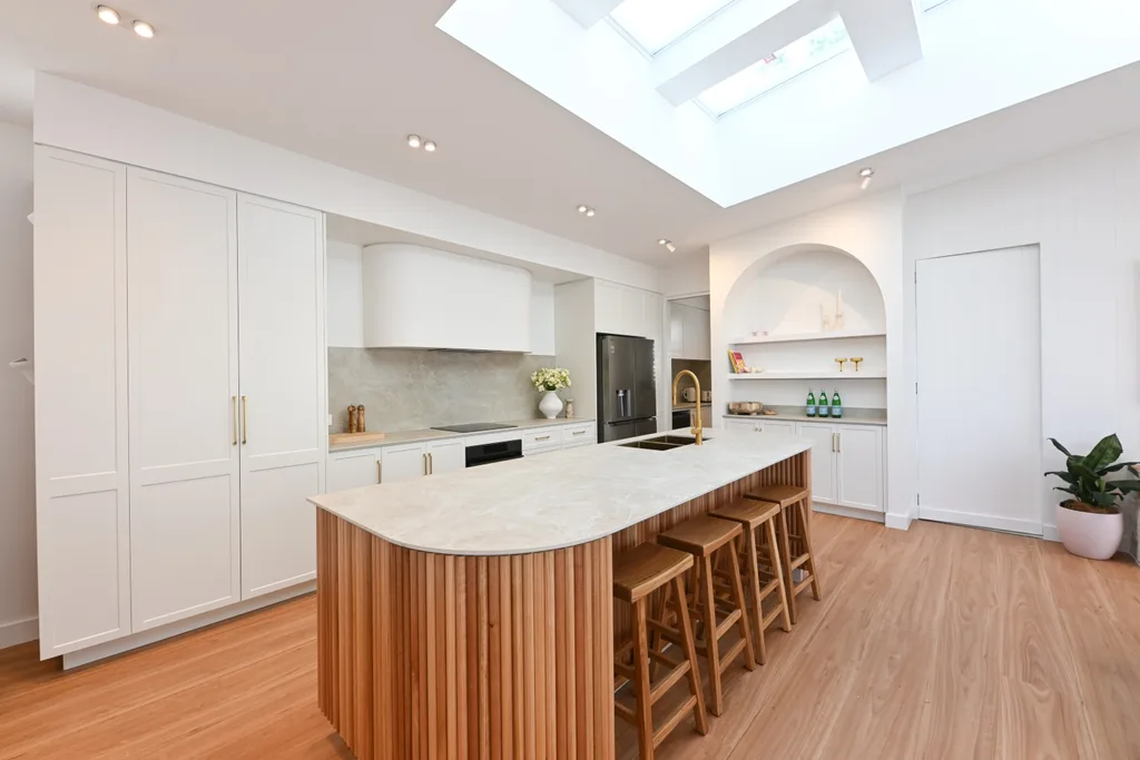 Rhys and Liam's dream kitchen with timber clad island bench base, wooden stools and simple white cabinetry.