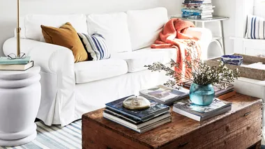 A modern living room with white sofaa, a wood coffee table, anda blue and white rug
