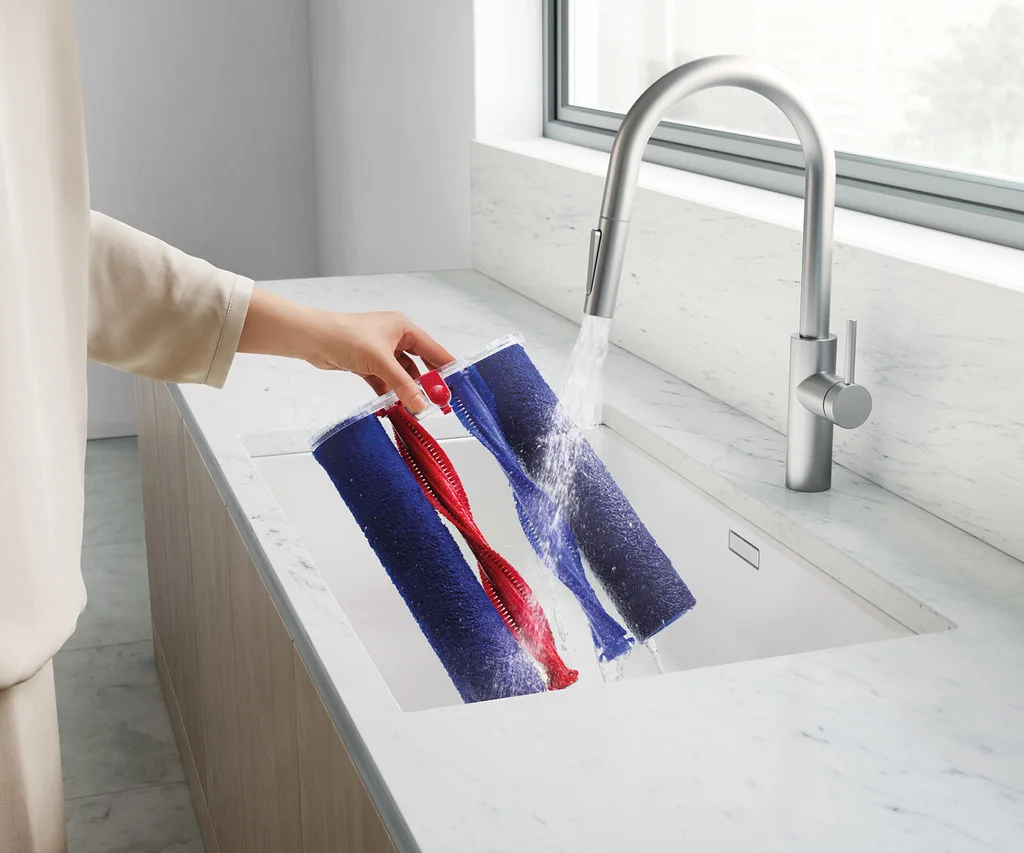 Illustration of washing the Dyson Wash G1 rollers and brushes in the sink,.