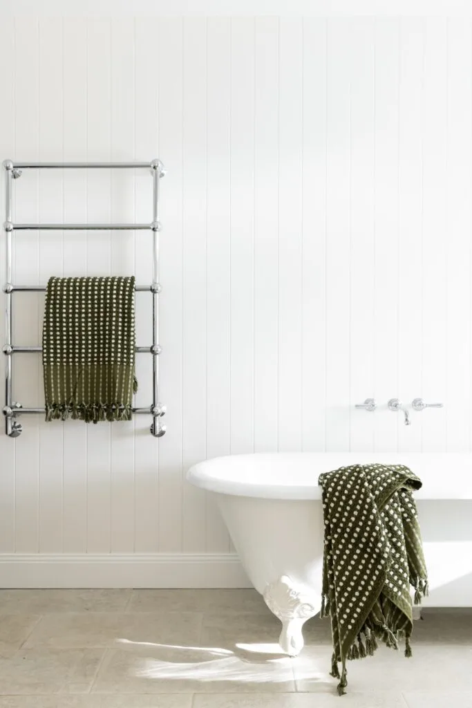 An all-white ensuite with a clawfoot bath and towel rail.