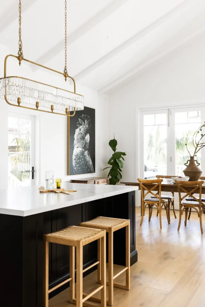 A Hamptons style kitchen with a black and white island and cockatoo artwork.