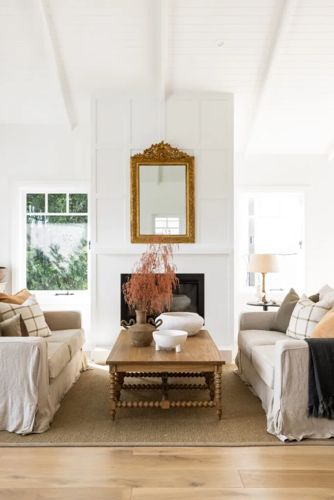 A Hamptons style living area with a timber coffee table and inset fireplace.