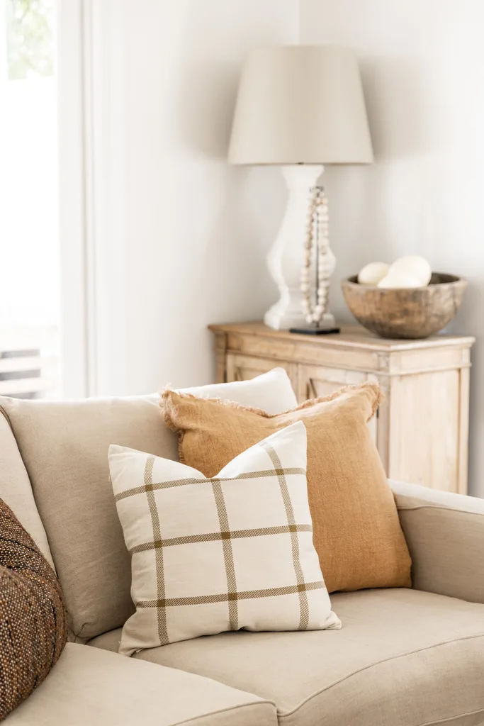 A beige sofa with brown and striped cushions.