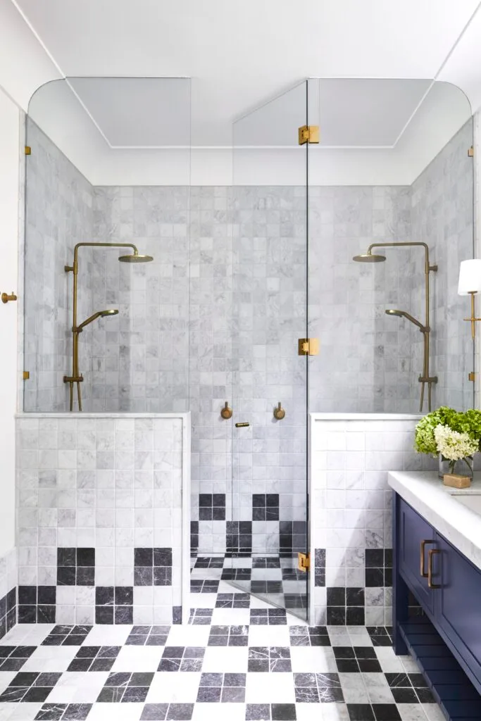 An ensuite with a double shower and marble black and white checked tiles.