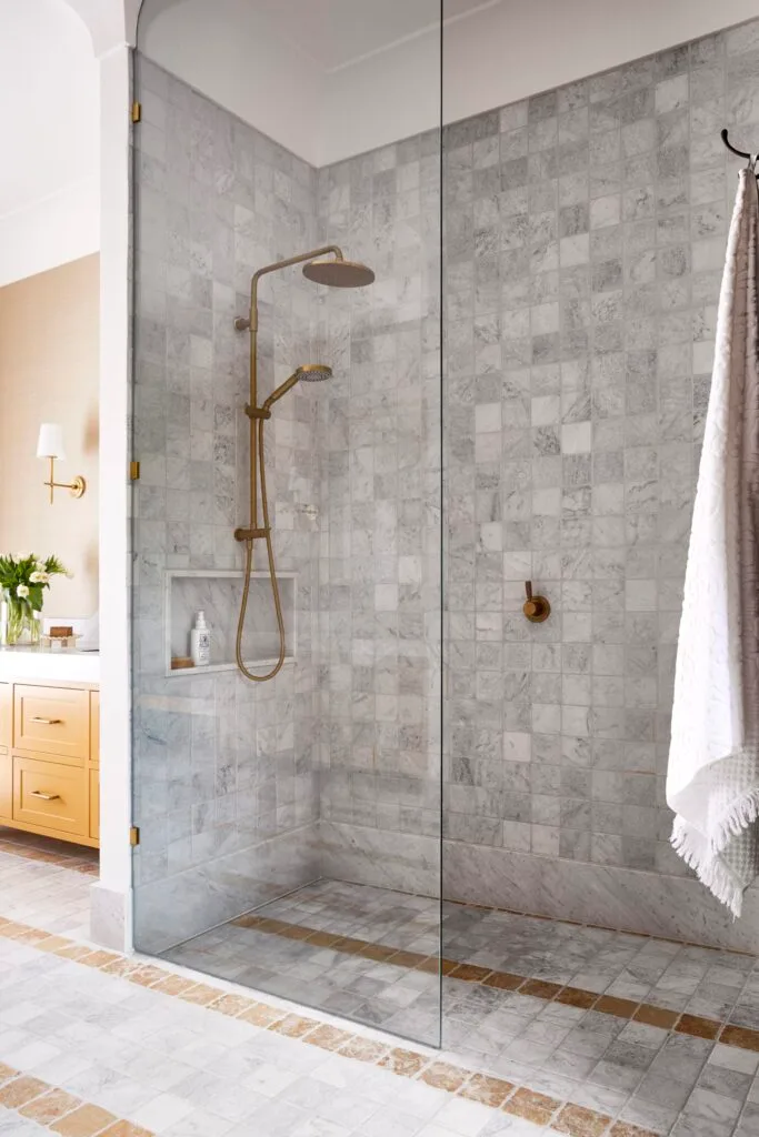 A grey tiled shower with brass tapware.