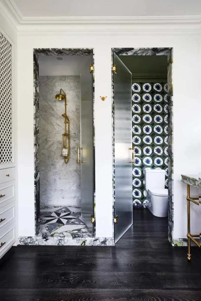 An ensuite with a side-by-side marble doorways to a shower and toilet.