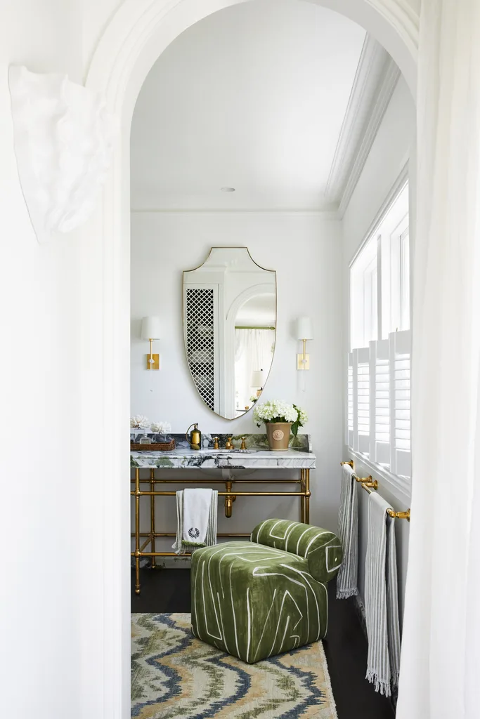 An archway leading into an ensuite with a stone vanity and green seat.