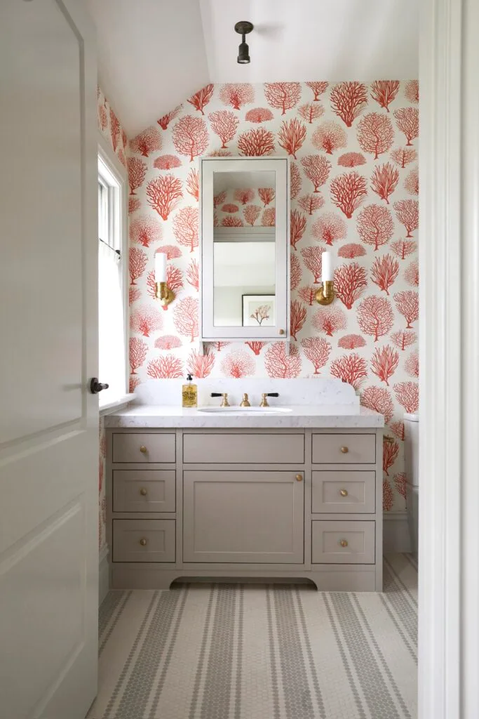 An ensuite with red tree-themed wallpaper and a marble-topped vanity.