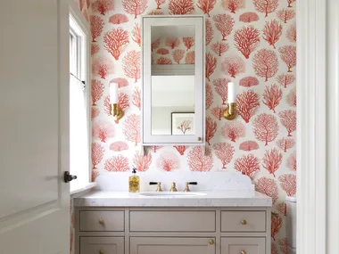 An ensuite with red tree-themed wallpaper and a marble-topped vanity.