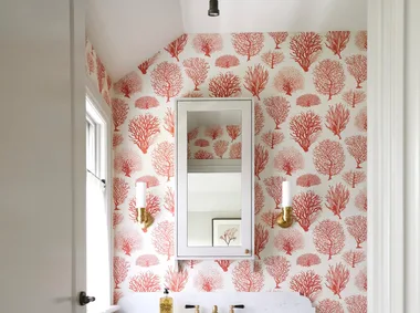 An ensuite with red tree-themed wallpaper and a marble-topped vanity.