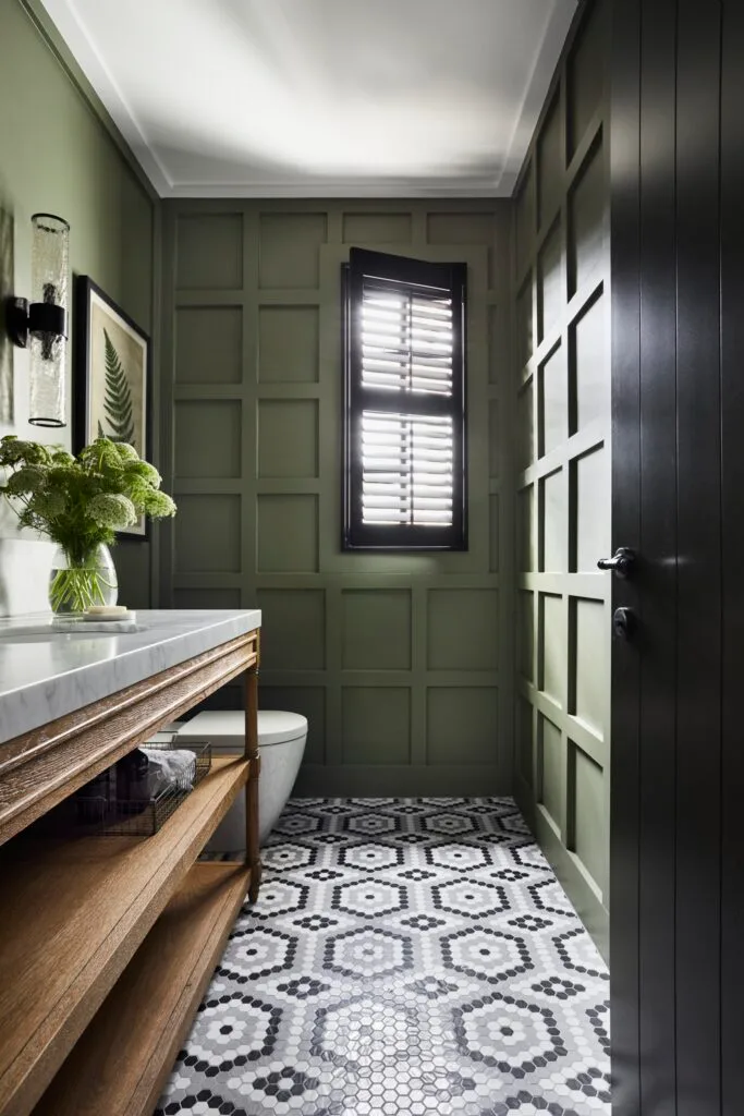 A forest green powder room with a mosaic tiled floor.