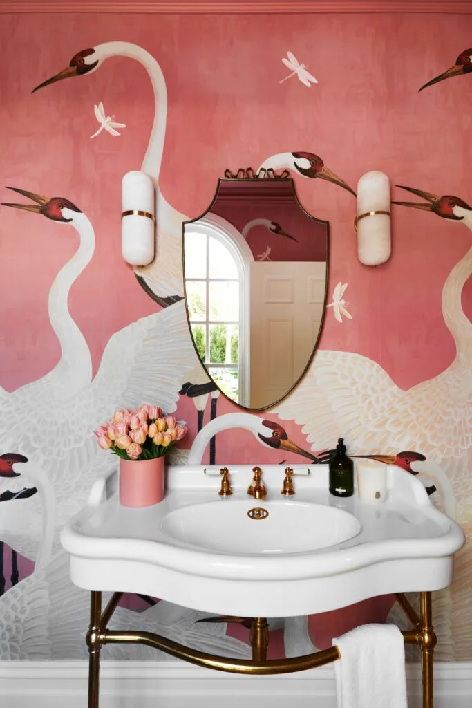 A classic pedestal basin and pink heron wallpaper.