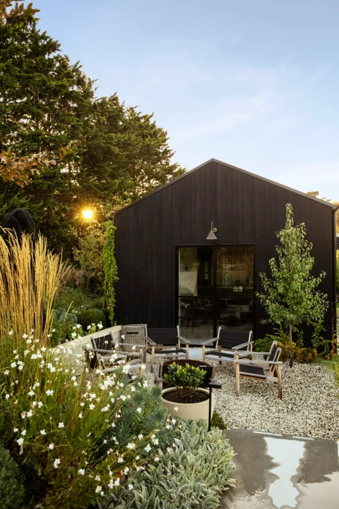 An outdoor seating area surrounded by seasonal blooms and grasses.