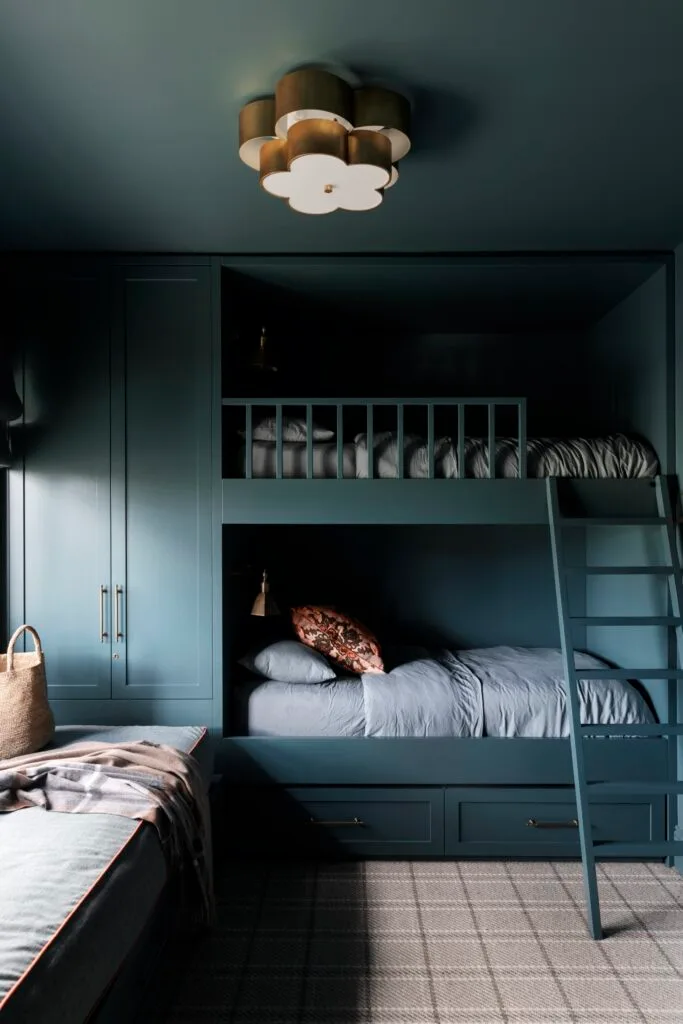 A bunk room painted in teal with a flower-shaped light.