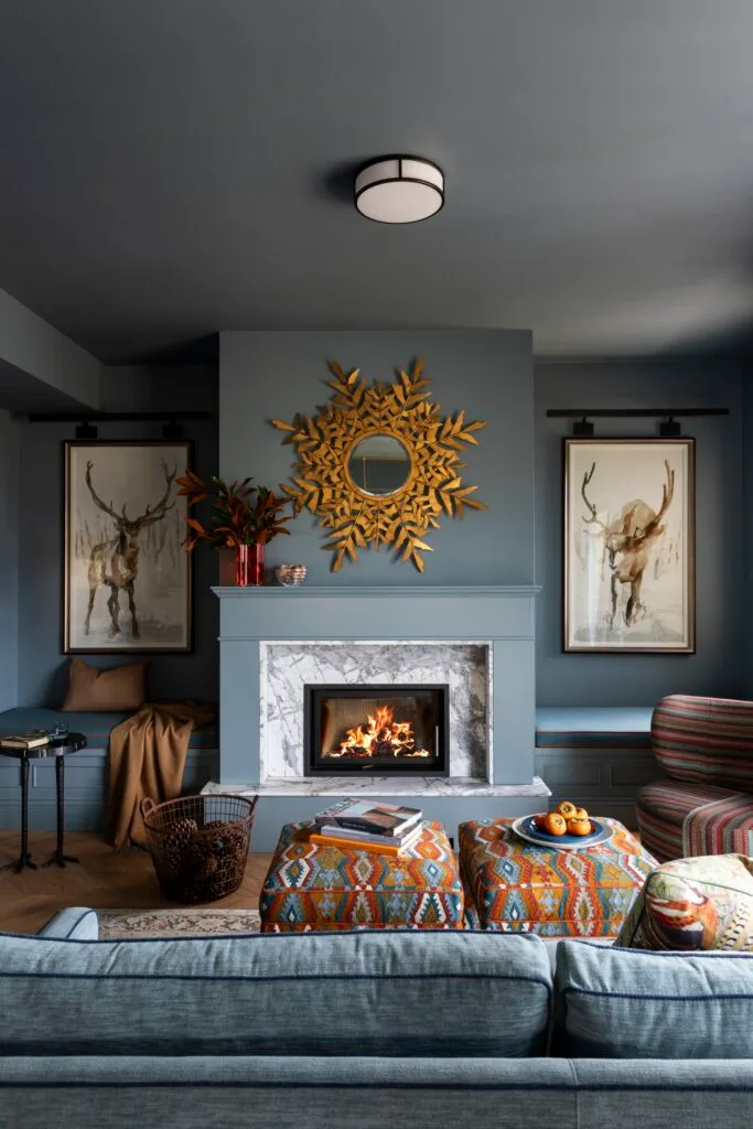 A luxury-style living room with a marble fireplace, framed deer art and a bronze leaf mirror.