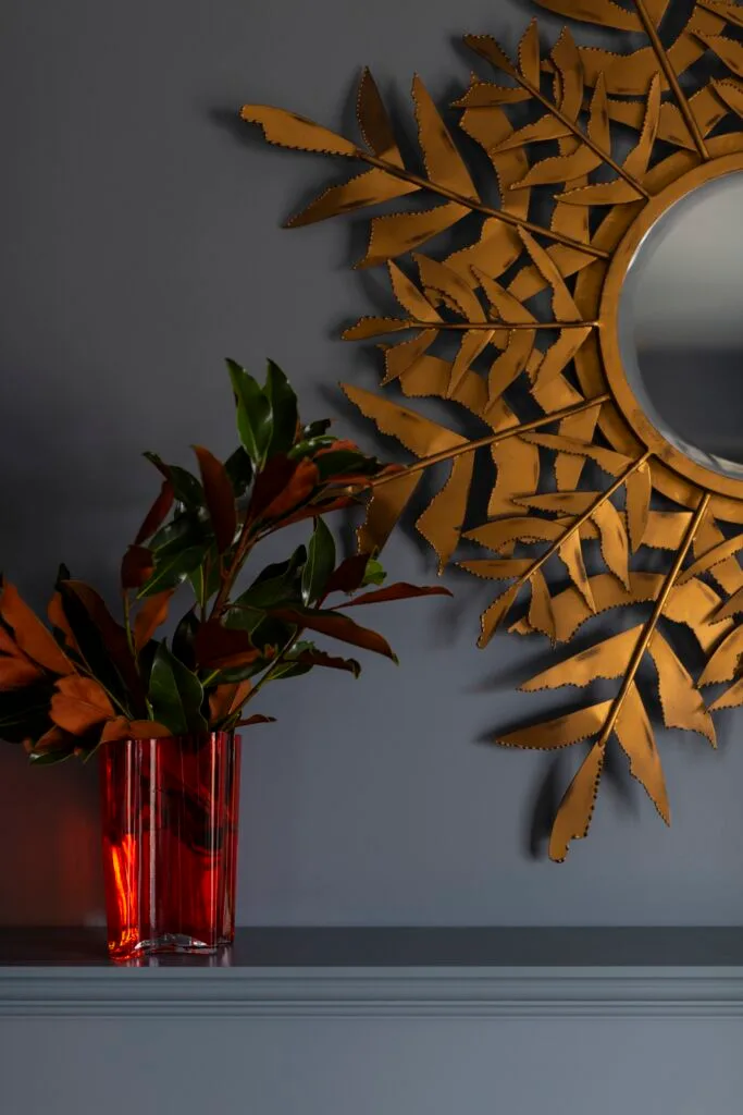 A bronze palm leaf mirror and glass vase.