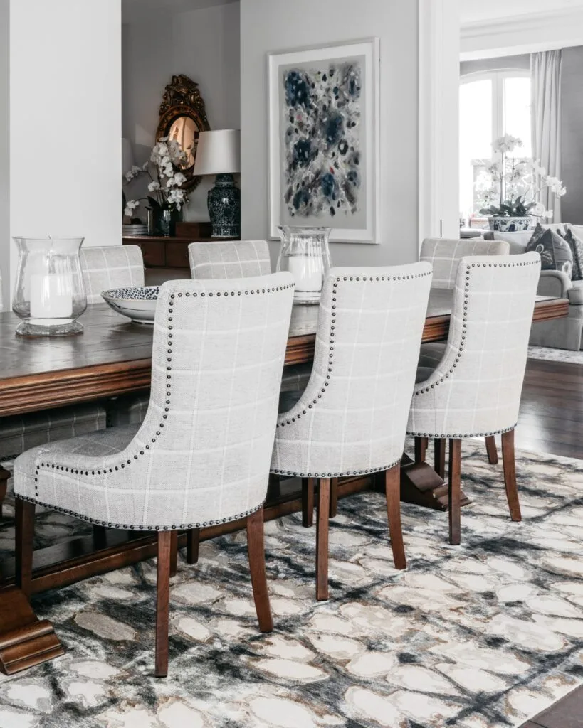 A classic style dining room with grey linen chairs and a timber table.