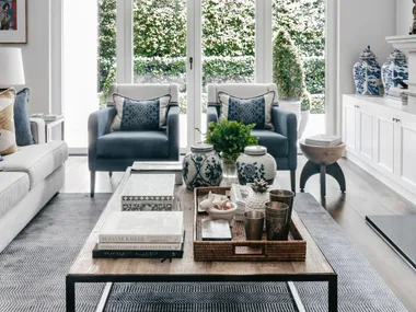 A formal style living area with blue armchairs, bifold glass doors and a timber coffee table.