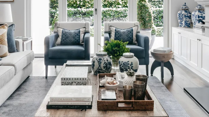 A formal style living area with blue armchairs, bifold glass doors and a timber coffee table.